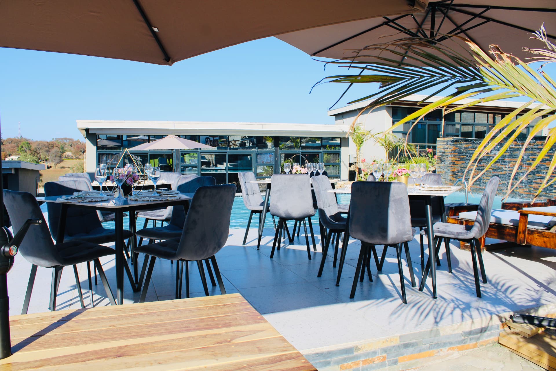 Dining tables set under umbrellas beside the pool