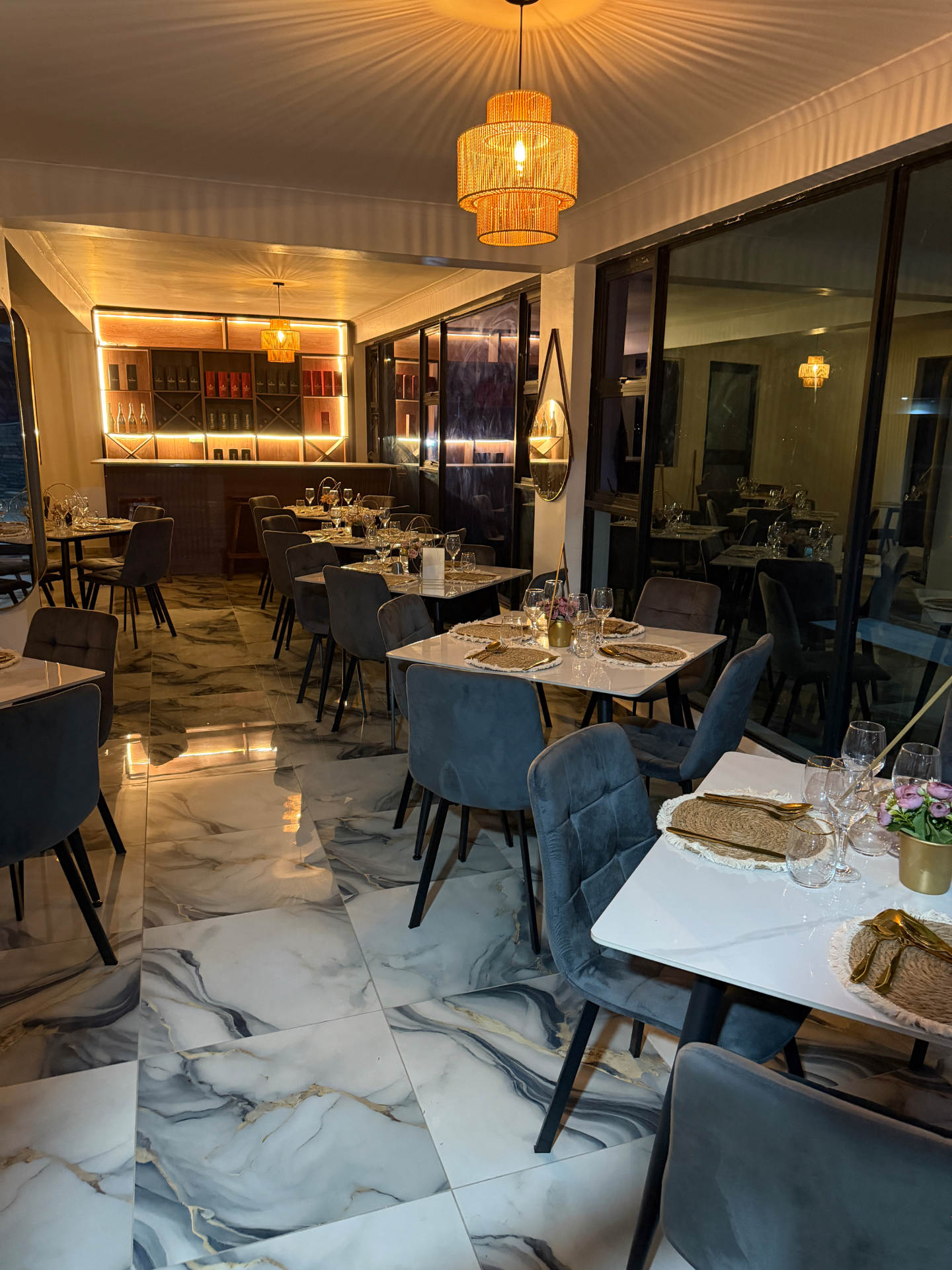 Lions Gate fine dining room with velvet chairs, candlelit tables and the backlit bar